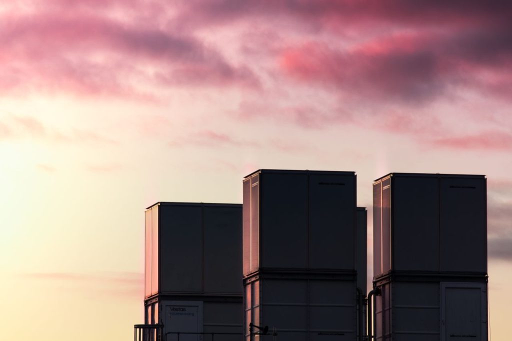 Silhouetted industrial containers against a vibrant sunset sky with pink clouds.
